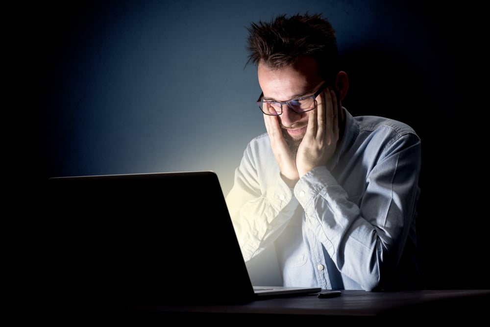 Young handsome businessman working late at night in the office with a dark background